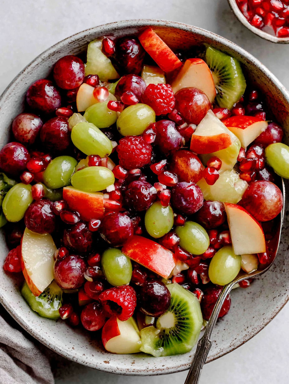 A bowl of fruit salad with grapes, kiwi, and apples.