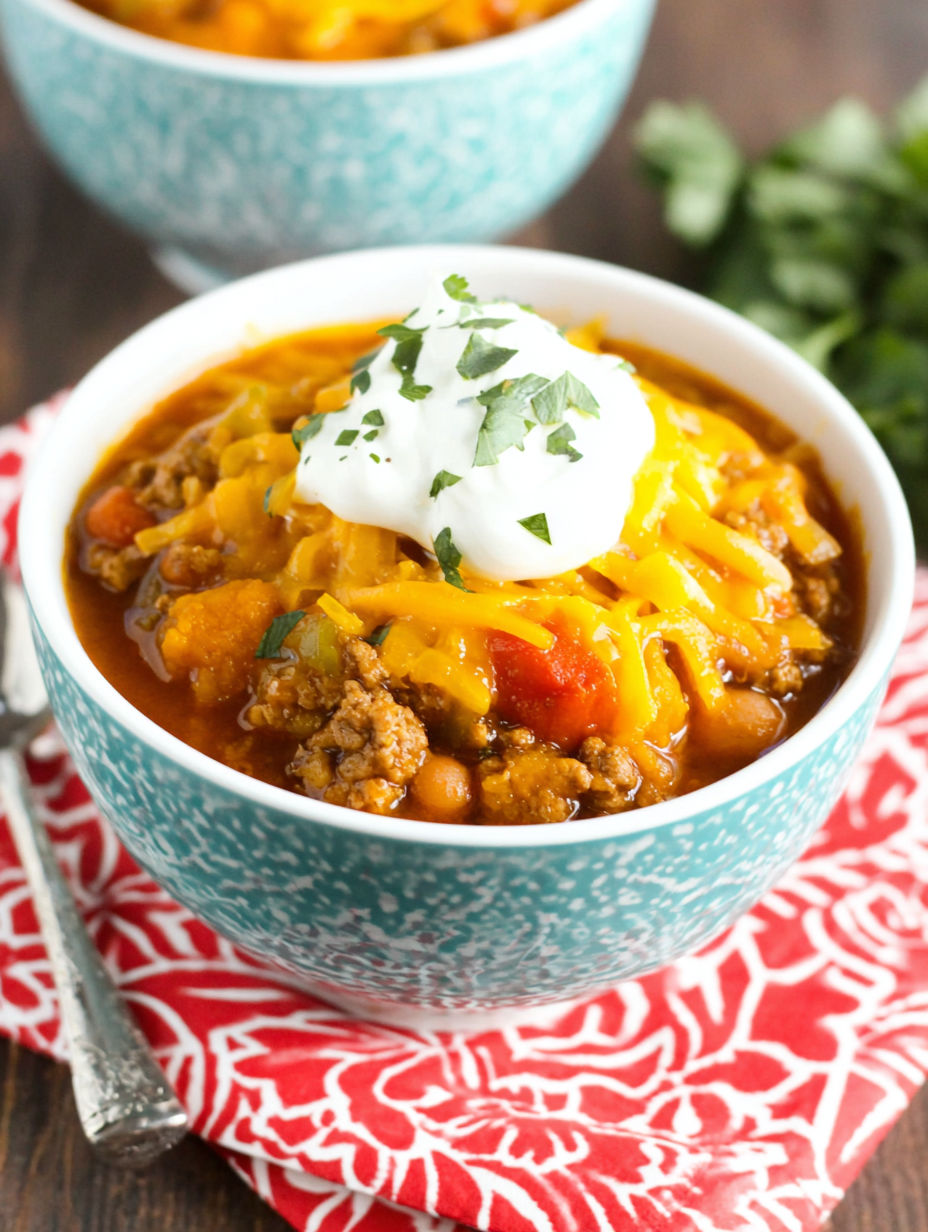 A bowl of chili with a dollop of sour cream on top.