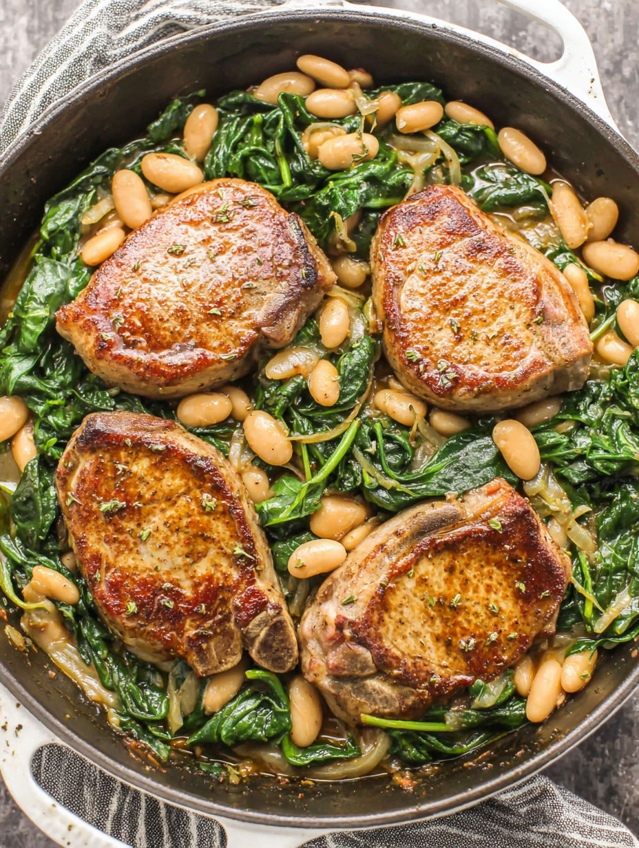 A skillet dinner with pork chops, white beans, and spinach.