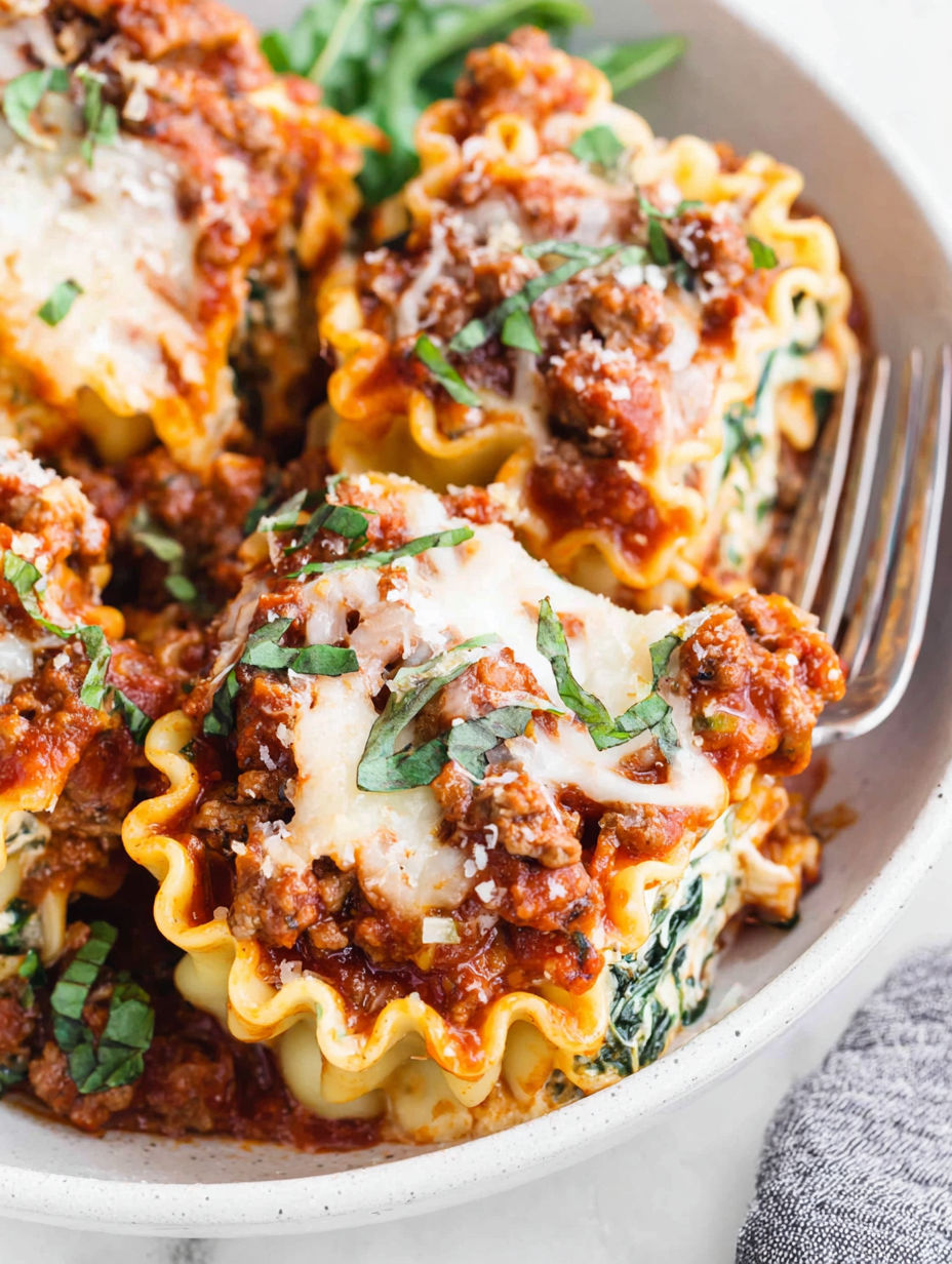 A plate of lasagna roll-ups with meat and cheese.