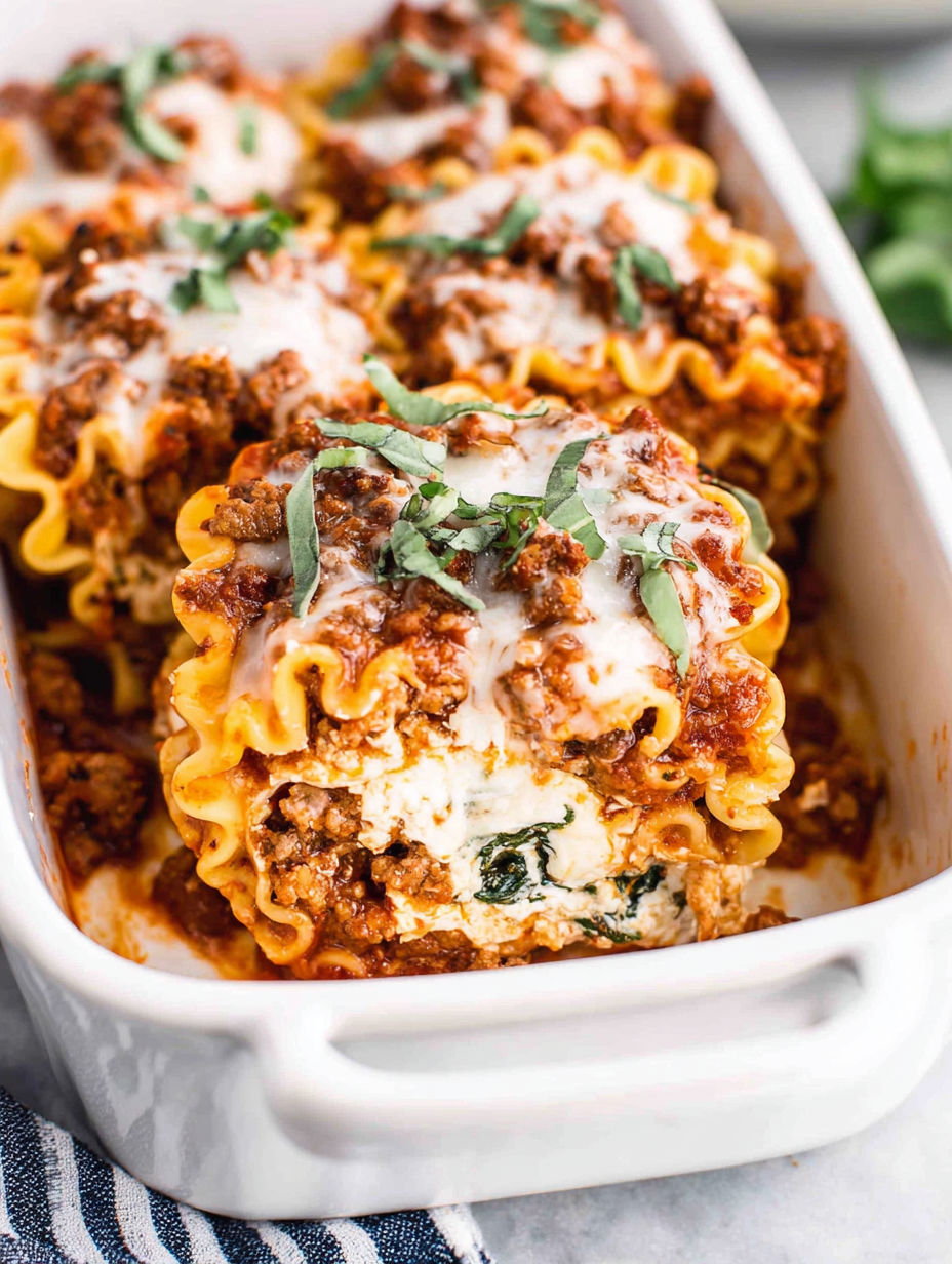 A dish of lasagna roll-ups with meat and cheese.