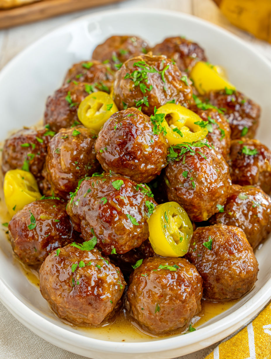 A plate of meatballs with yellow peppers and green onions.