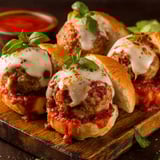 A plate of meatball sandwiches with cheese.