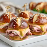 A plate of ham and cheese on pretzel sliders.