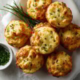 A plate of muffins with green toppings.