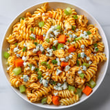 A bowl of pasta salad with chicken and blue cheese.