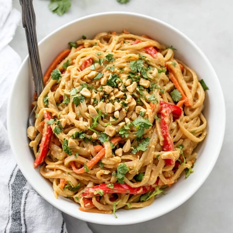 A bowl of noodles with peanut butter and vegetables.