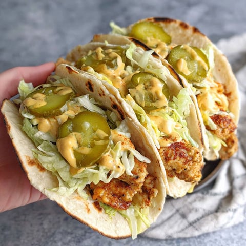 A hand holding a chicken big mac taco.