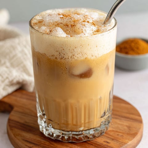 A glass of iced chai tea latte with pumpkin cold foam.