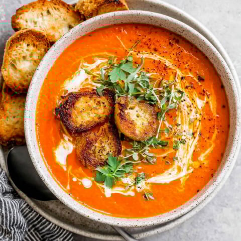 A bowl of tomato bisque with a spoon in it.