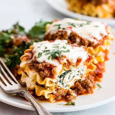 A plate of lasagna roll-ups with cheese and spinach.