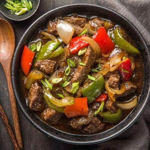 A bowl of beef and peppers in a slow cooker.