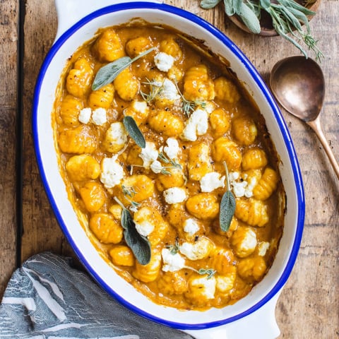 A bowl of pumpkin gnocchi bake with cheese and herbs.