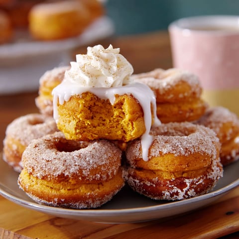 A plate of baked pumpkin doughnuts with white icing.