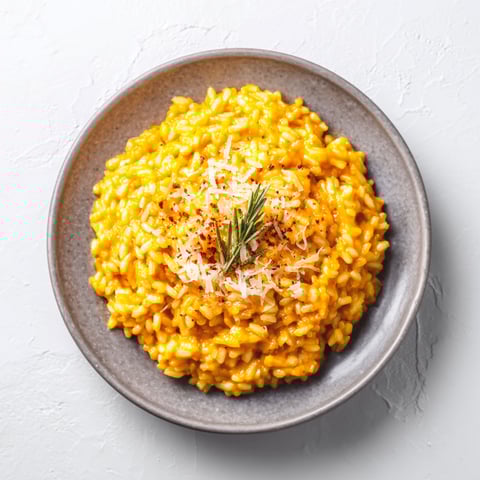 A bowl of creamy pumpkin risotto with cheese on top.