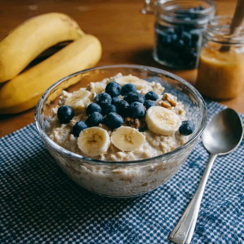 A bowl of oatmeal with bananas and blueberries.