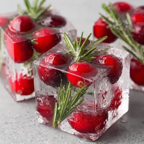 A close up of a red berry in a cube of ice.