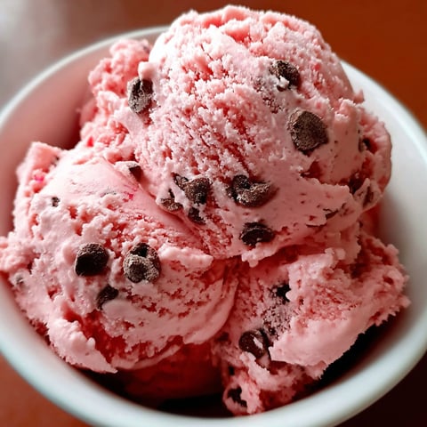 A bowl of pink ice cream with chocolate chips.