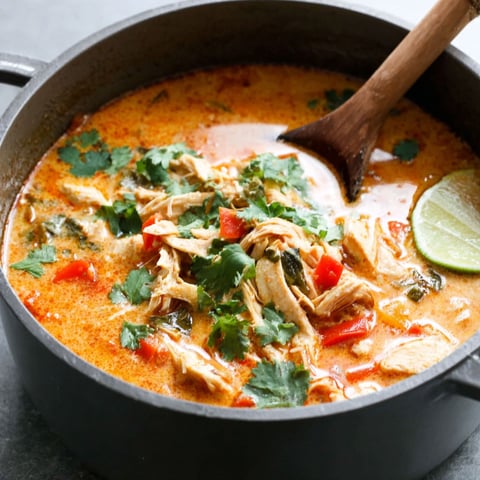 A bowl of soup with a wooden spoon in it.