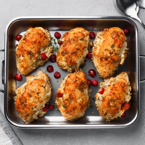 A pan of stuffed chicken breasts with a spoon nearby.