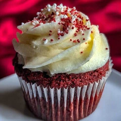 A red velvet cupcake with white frosting.