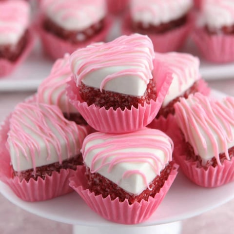 Heart shaped cupcakes with white frosting and pink frosting.